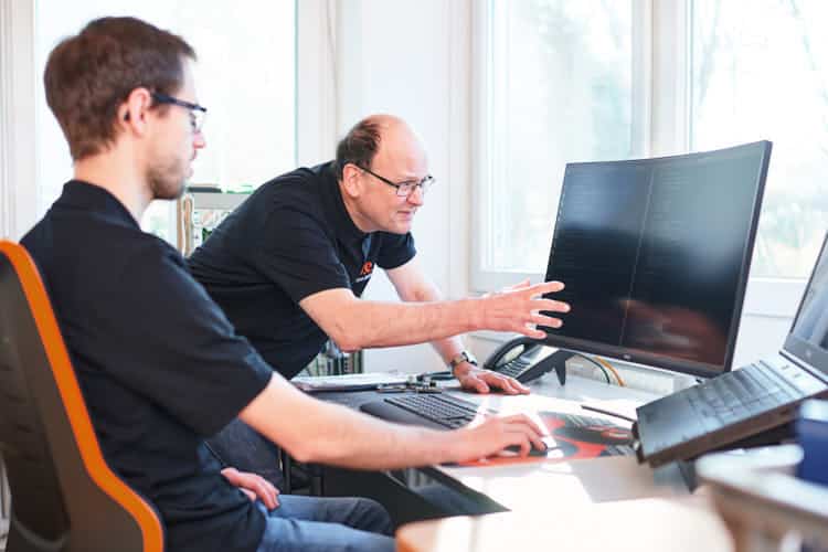 Generationsübergreifend: Firmengründer Helmut Singer erklärt einem jungen Entwickler den Coder einer Schrittmotorsteuerung